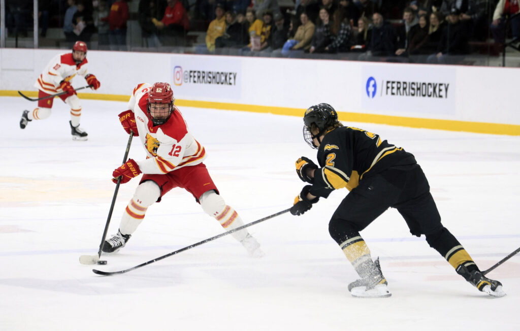 Forward Caden Brown fights for the puck with a Michigan Tech defender during on Dec. 12.